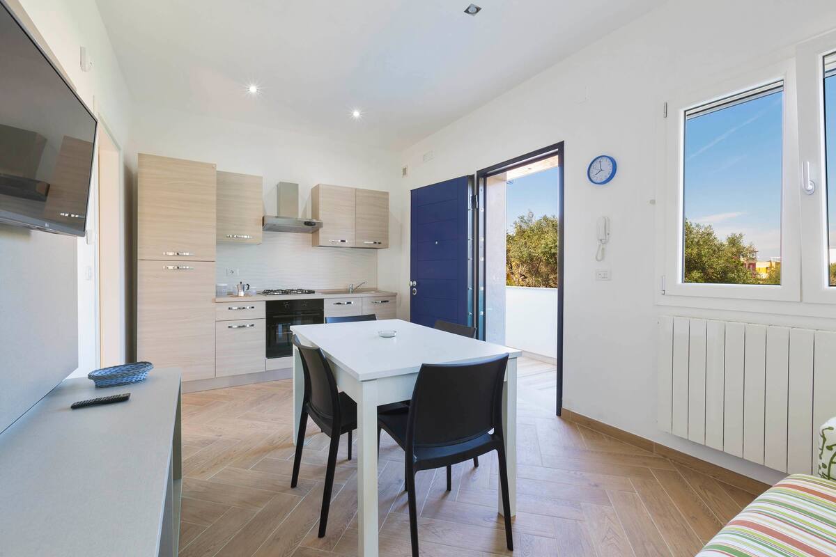 A modern kitchen with a dining area, a large window, and a view of the outdoors.