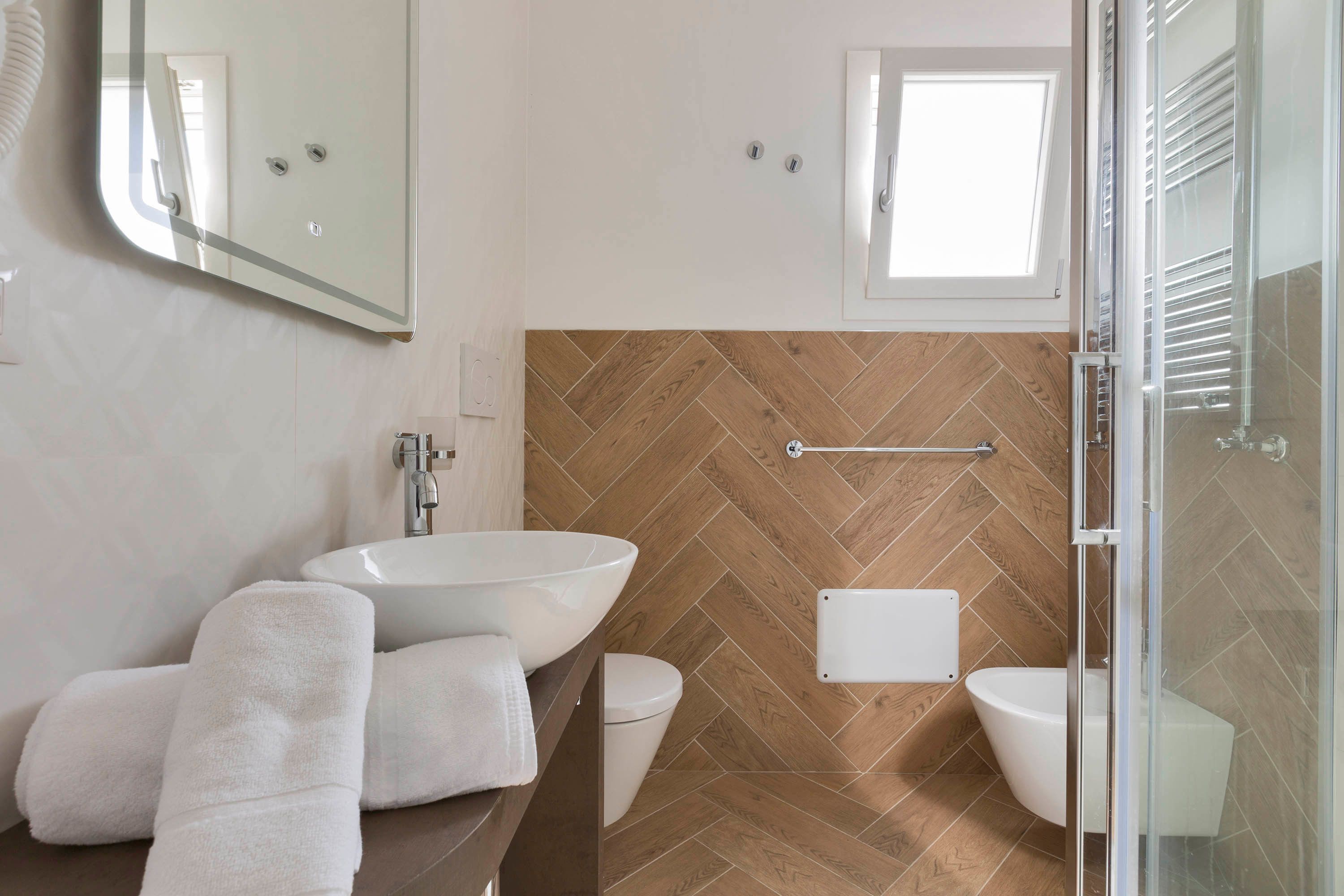 A modern bathroom with a large sink, a toilet, and a shower area.