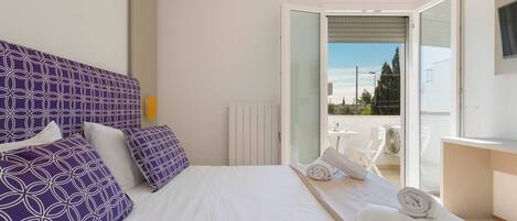 A hotel room with a bed, a bathroom, and a balcony.