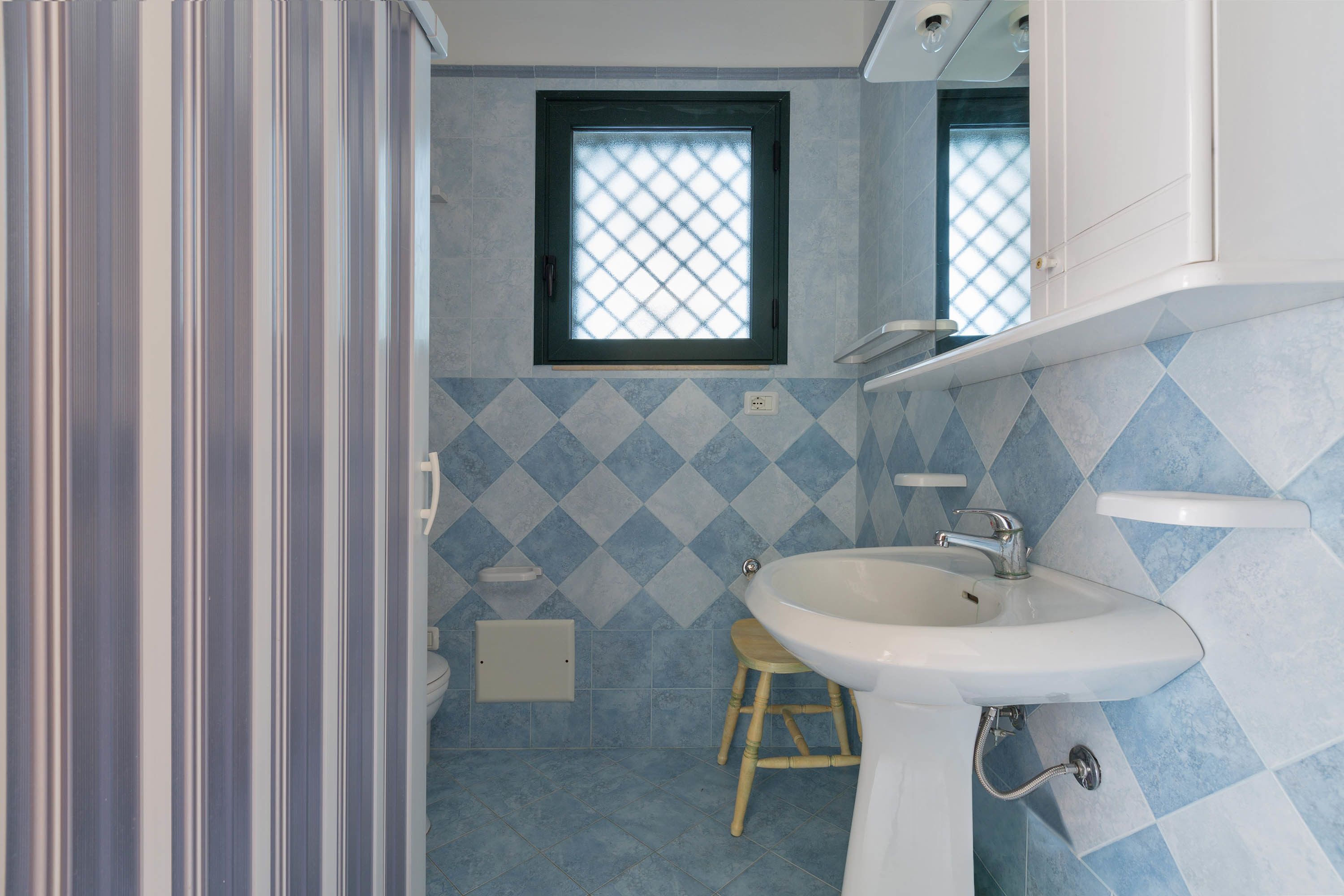 A bathroom with a window, a sink, and a toilet.