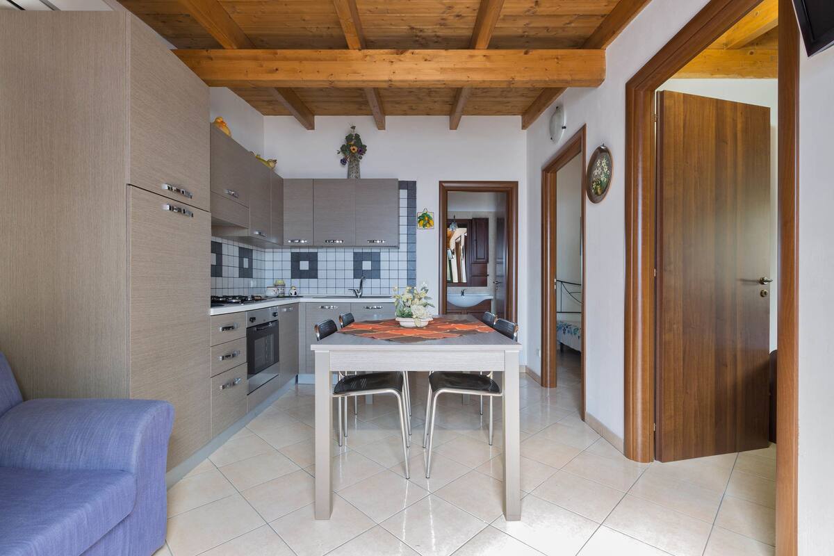 Una cocina moderna con vigas de madera, una mesa de comedor con sillas y un sofá.