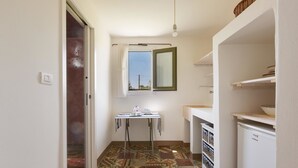 Un baño pequeño y estrecho con piso de baldosas estampadas, un lavamanos blanco, un espejo y una mesita con artículos de tocador.