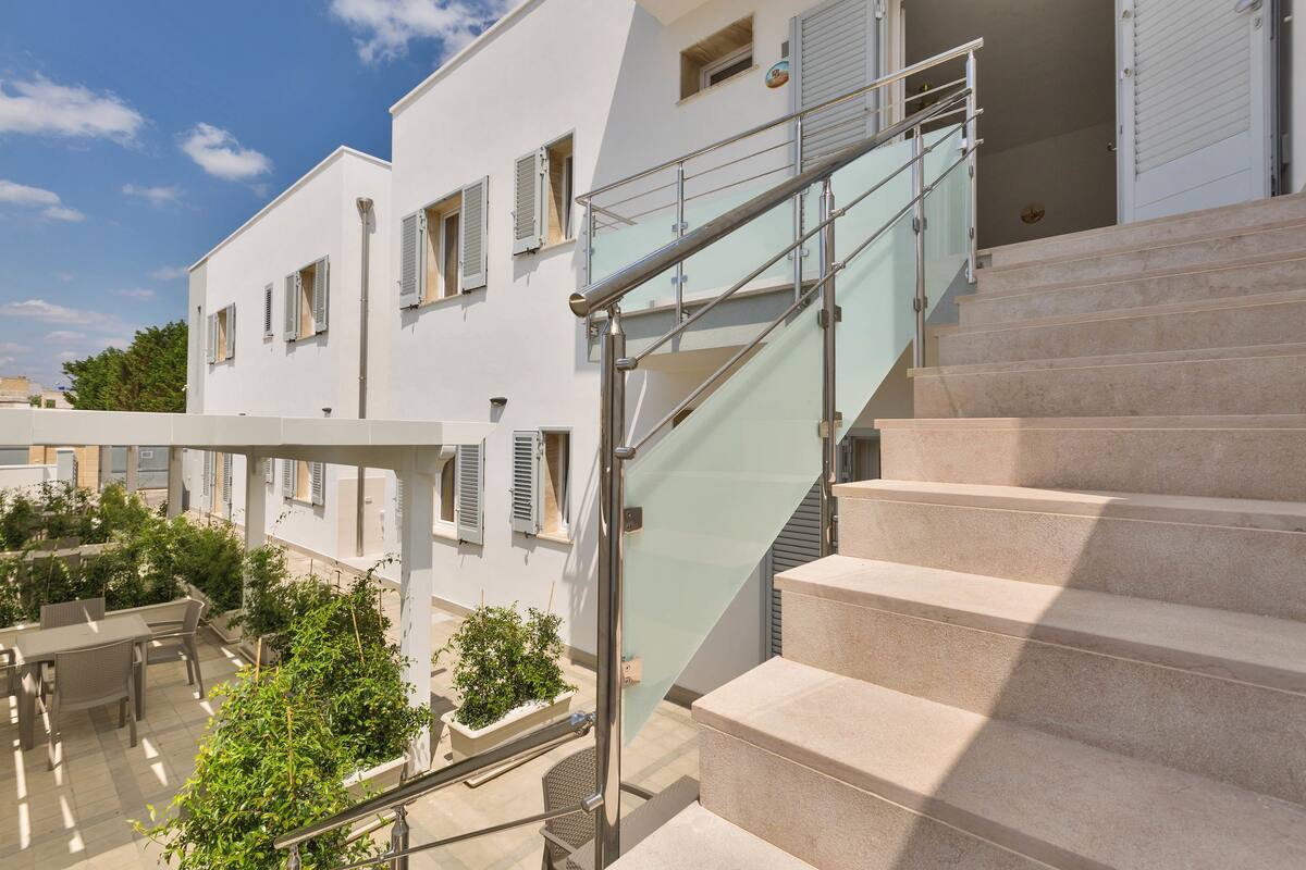 A modern building with a glass staircase leading to a balcony.