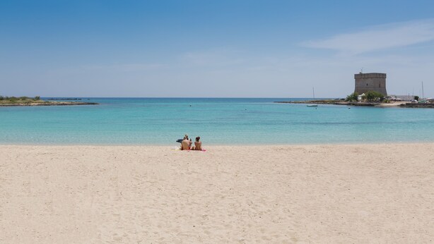 A beach with a tower in the background. - Residence Tabù (Porto Cesareo)