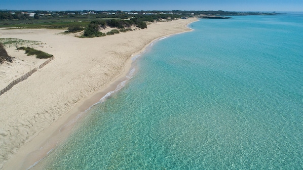 A coastal beach with clear turquoise waters and sandy shores.
