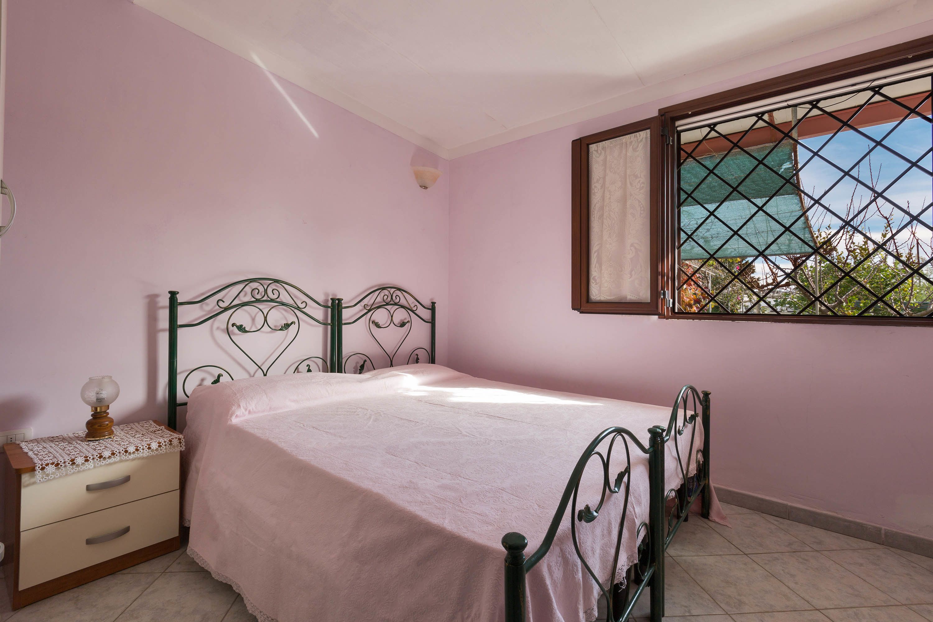 A bedroom with a single bed, a nightstand, a window with a view, and a ceiling fan.