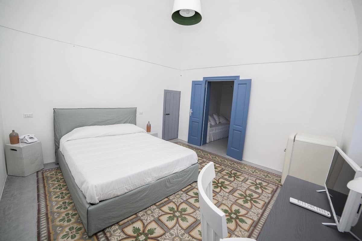 Quarto com cama, escrivaninha, cadeira, guarda-roupa e porta de guarda-roupa aberta.