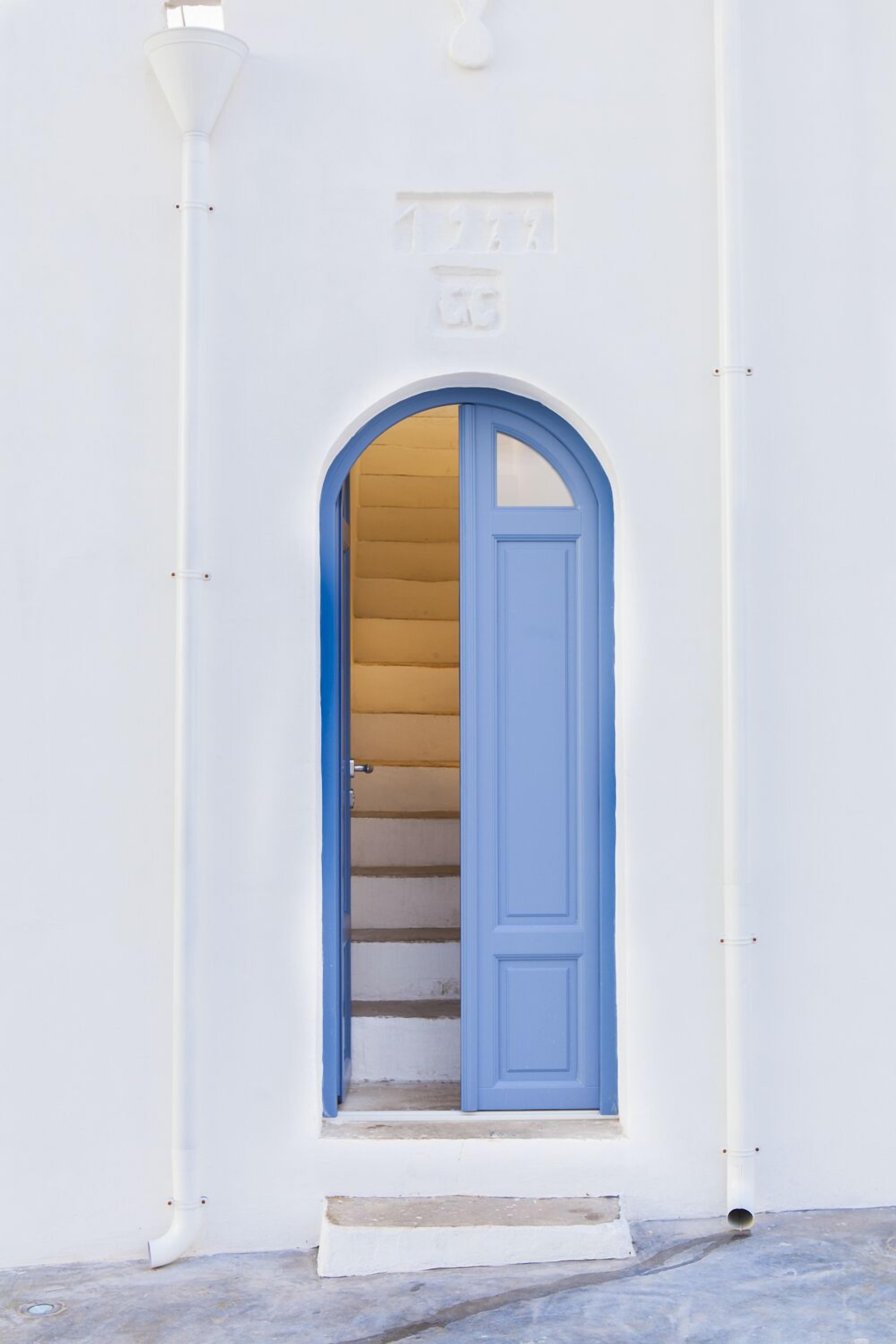 A white building with a blue door and a small set of steps leading to an entrance.