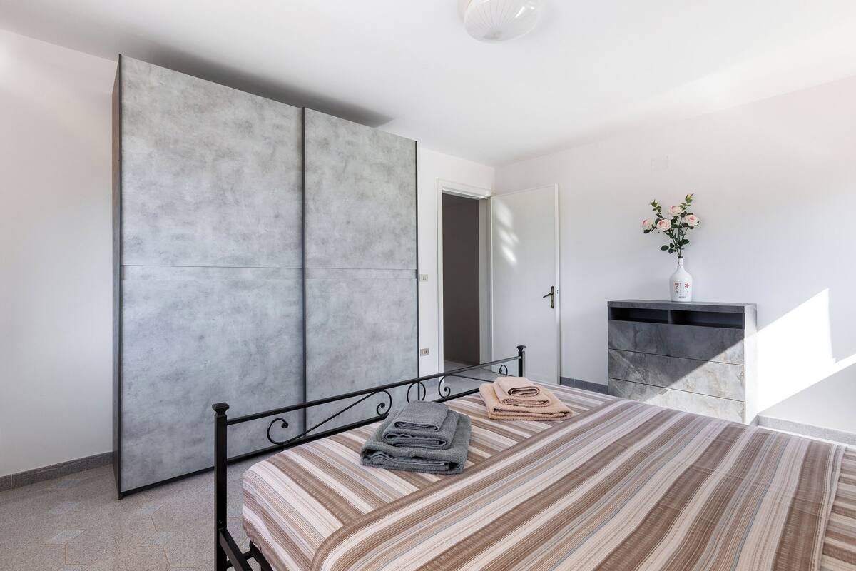 A bedroom with a bed, a wardrobe, a dresser, and a vase with flowers.