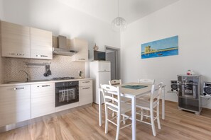 A modern kitchen with white cabinets, a stove, oven, and a dining area with white chairs and a table.
