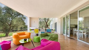 A modern outdoor living area with colorful seating and a glass door leading to a kitchen. - Villa Carlita (Carovigno)