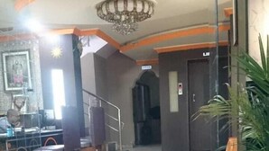 Un hall d’entrée avec un sol en marbre, une moquette rouge, un lustre et un escalier.