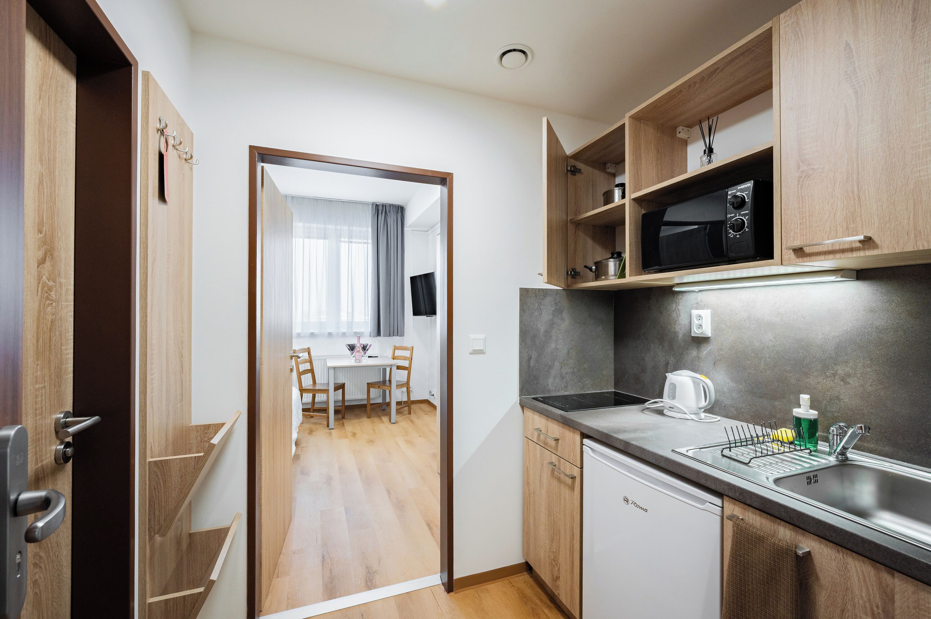 A compact kitchen with a microwave, sink, and wooden cabinets.