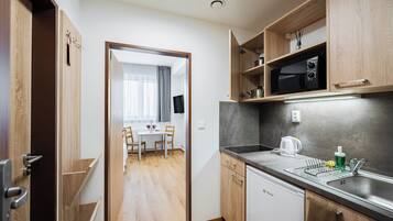 A compact kitchen with a microwave, sink, and wooden cabinets.