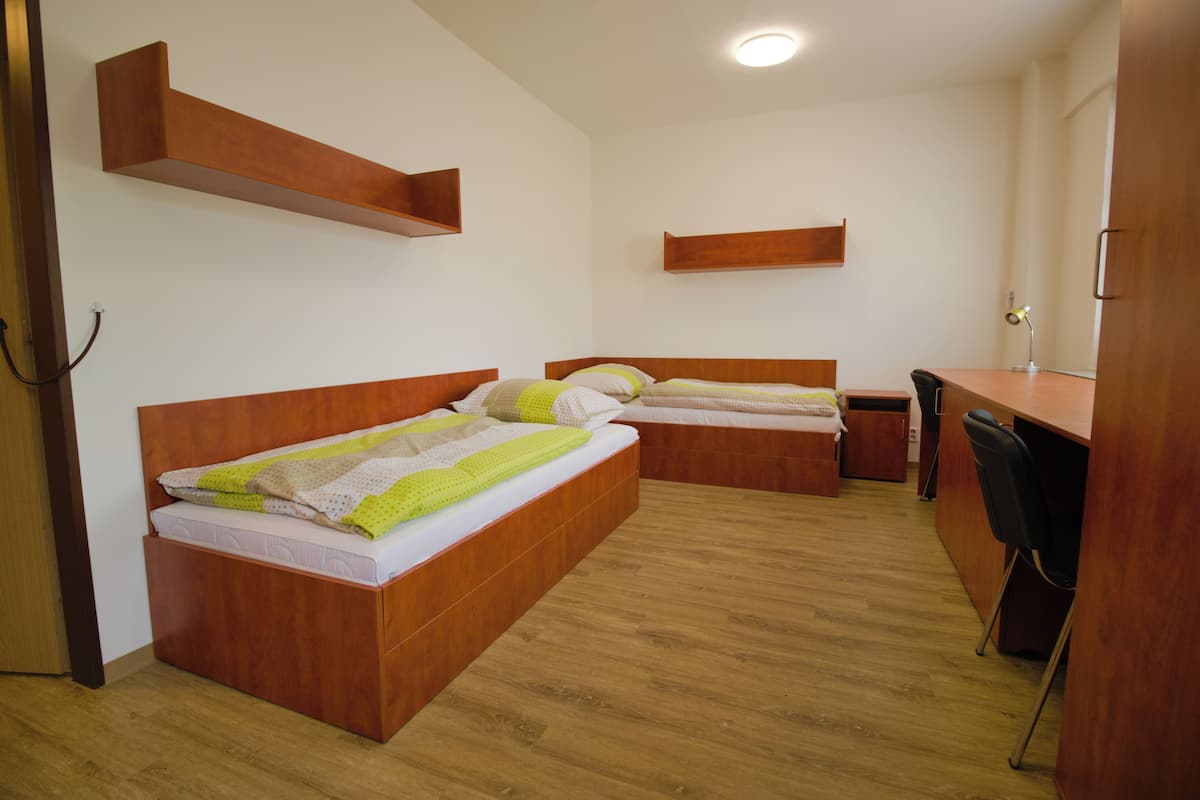 A room with two wooden beds, a desk, and a chair.