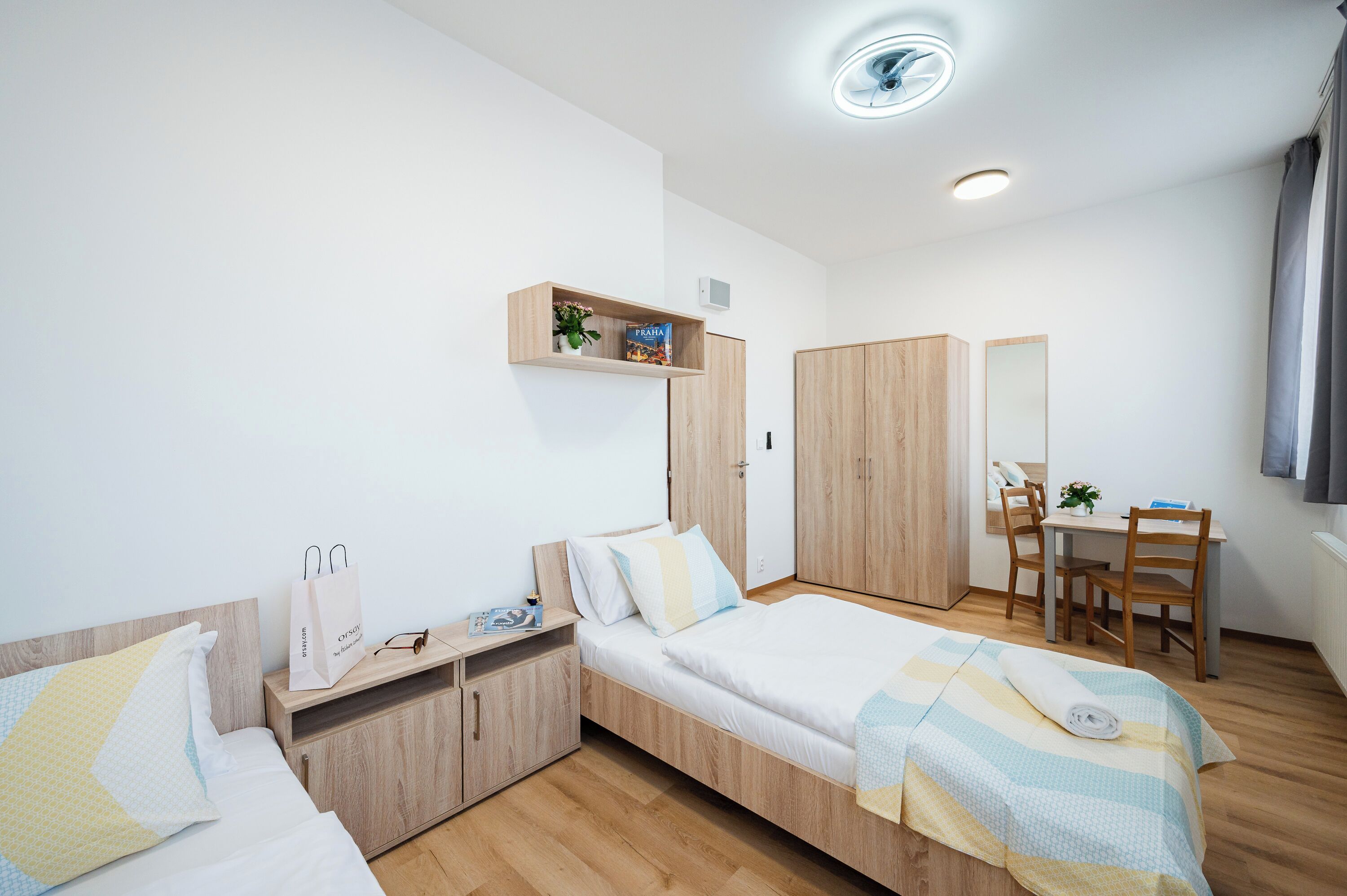 Ein modernes Schlafzimmer mit Bett, Nachttisch, Kleiderschrank und einer kleinen Schreibtischzeile mit Stuhl.