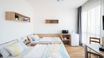 A hotel room with two beds, a desk, a microwave, and a small refrigerator.
