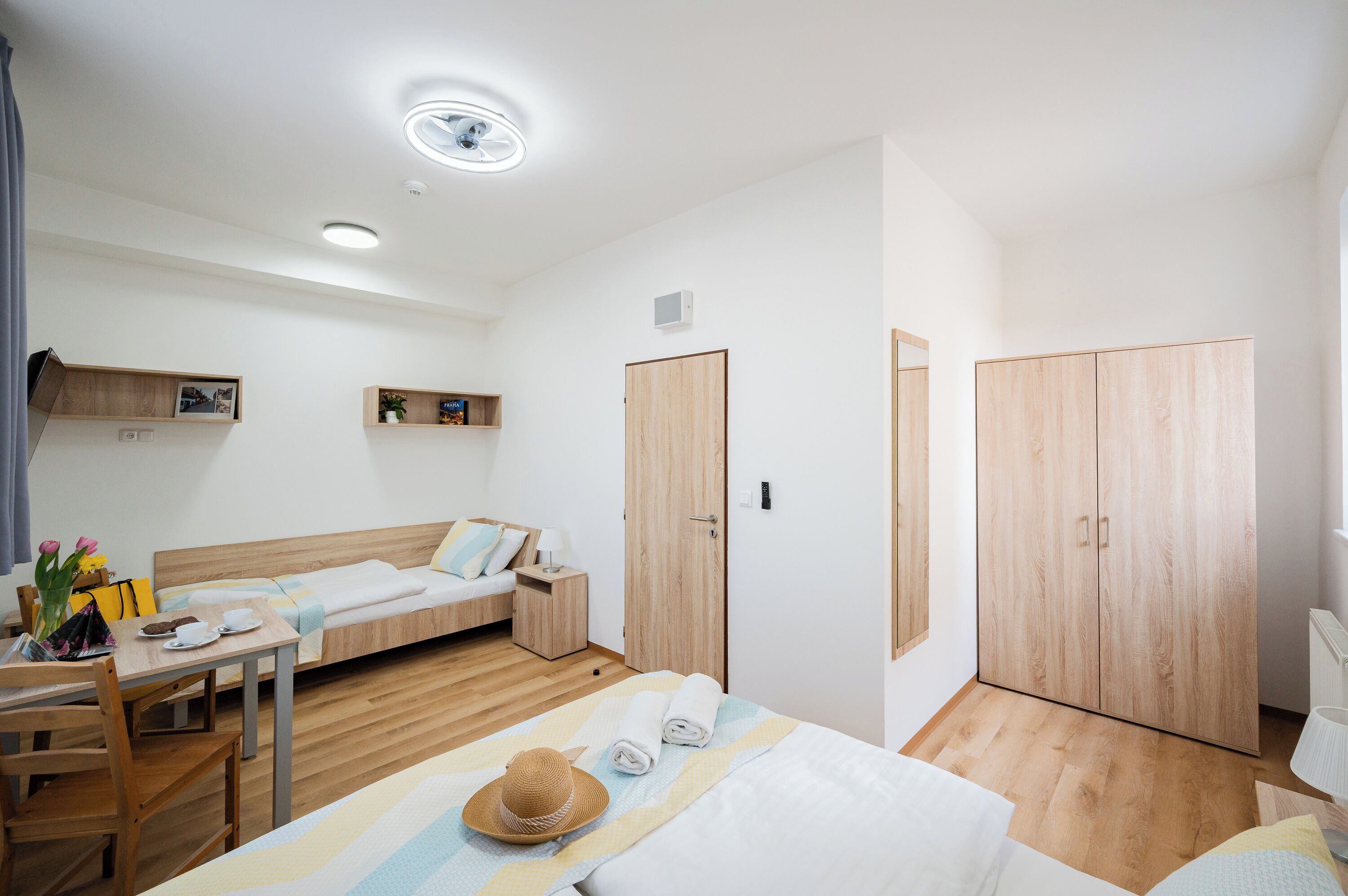 Ein Hotelzimmer mit Bett, Schreibtisch, Stuhl, Kleiderschrank und einem kleinen Tisch mit Hut und Handtüchern.