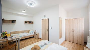 Ein Hotelzimmer mit Bett, Schreibtisch, Stuhl, Kleiderschrank und einem kleinen Tisch mit Hut und Handtüchern.