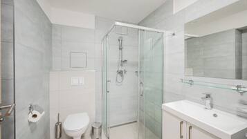 A modern bathroom with a glass-enclosed shower, a white sink, and a large mirror.