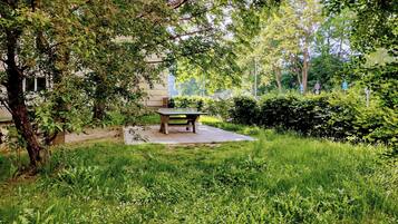 A park with a table and benches, surrounded by greenery and trees.