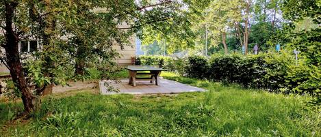A park with a table and benches, surrounded by greenery and trees.
