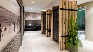 Un couloir d’hôtel moderne agrémenté d’éléments en bois, d’une grande plante et d’une fresque murale.