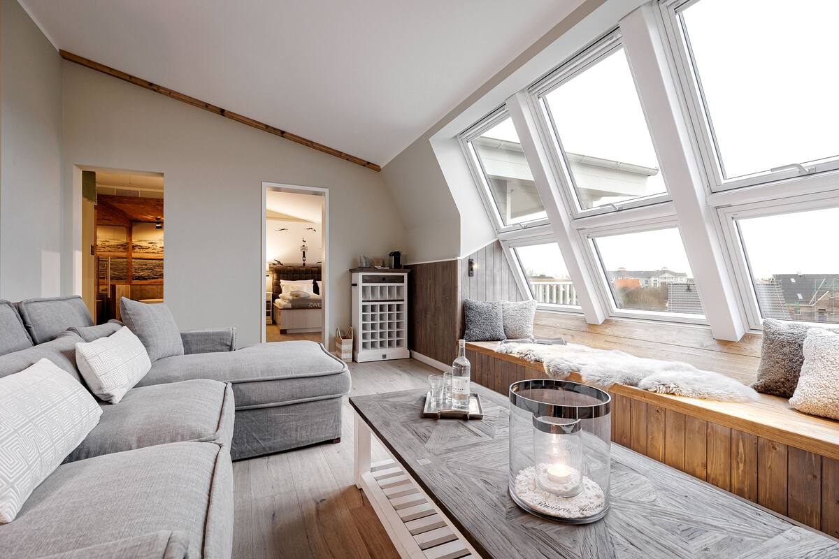 A modern living room with a sectional sofa, a wooden coffee table, and a view of the city through large windows.