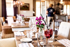 A restaurant setting with tables set for dining, clear glassware, and a candle on each table. - Strandhotel Zweite Heimat (St. Peter-Ording)