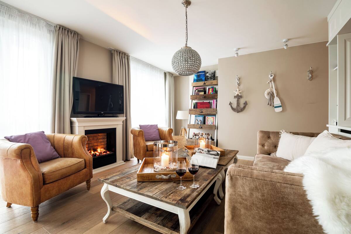 A living room with a fireplace, leather sofas, a coffee table, and a bookshelf.