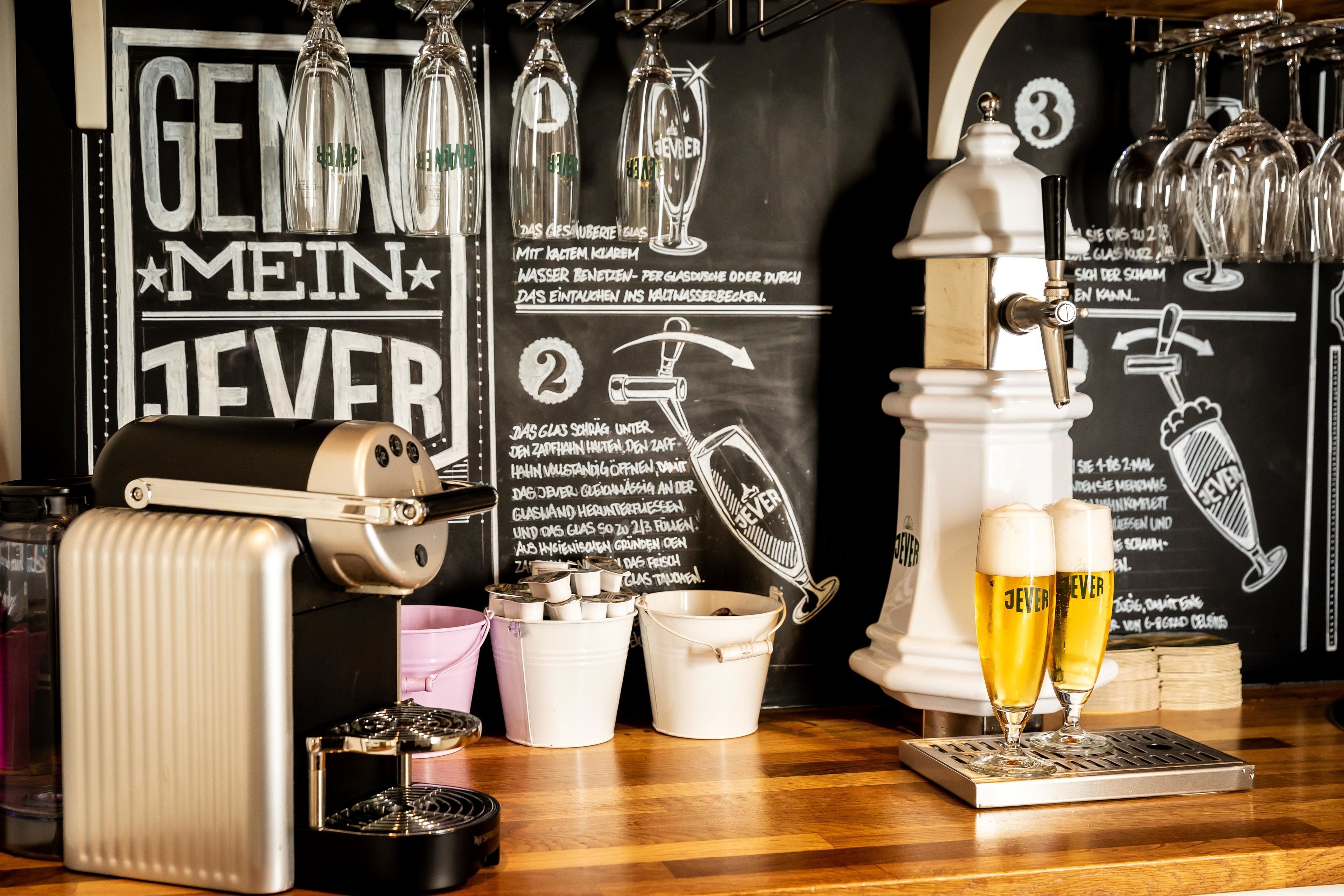 A bar area with a beer tap, glasses, and a chalkboard with text and illustrations.