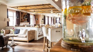 Un vaste espace de vie doté d’un plafond en bois, d’un îlot central avec des sièges et d’un grand bocal en verre posé sur une table.