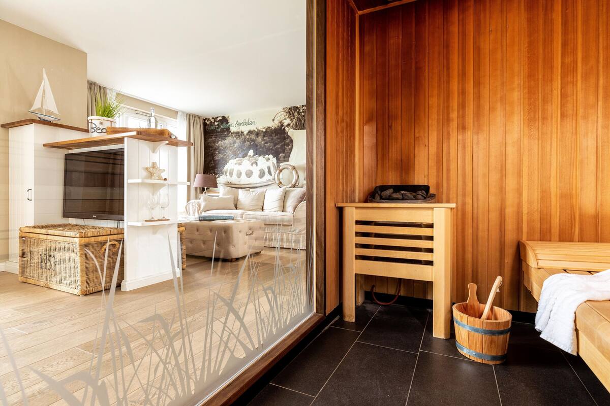 A modern room with a wooden sauna, a white sofa, a wooden table, and a wicker basket.