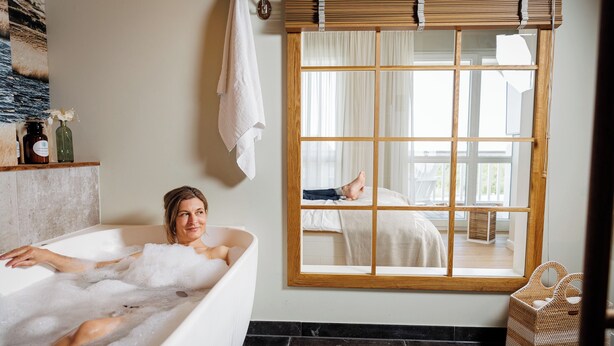 Une salle de bain avec une baignoire, une grande fenêtre et un miroir.