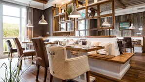 Un espace repas comprenant un banc en bois, des chaises et des luminaires suspendus.