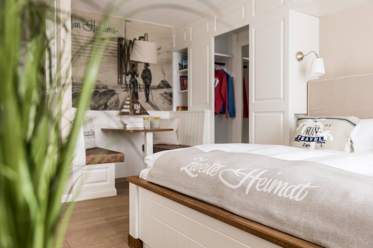 A neatly arranged hotel room with a bed, a bedside table, a lamp, and a wall with a poster.