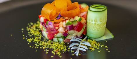A dish with various colorful ingredients and garnishes on a dark plate.