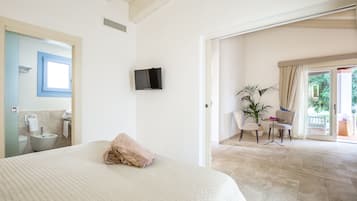 Ein Schlafzimmer mit einem großen Bett, einem an der Wand montierten Fernseher und Blick auf den Balkon.
