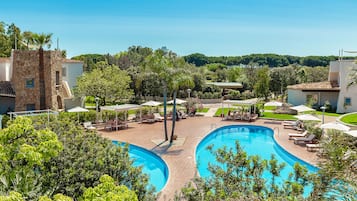 A resort with a large pool, lounge areas, and a stone building.