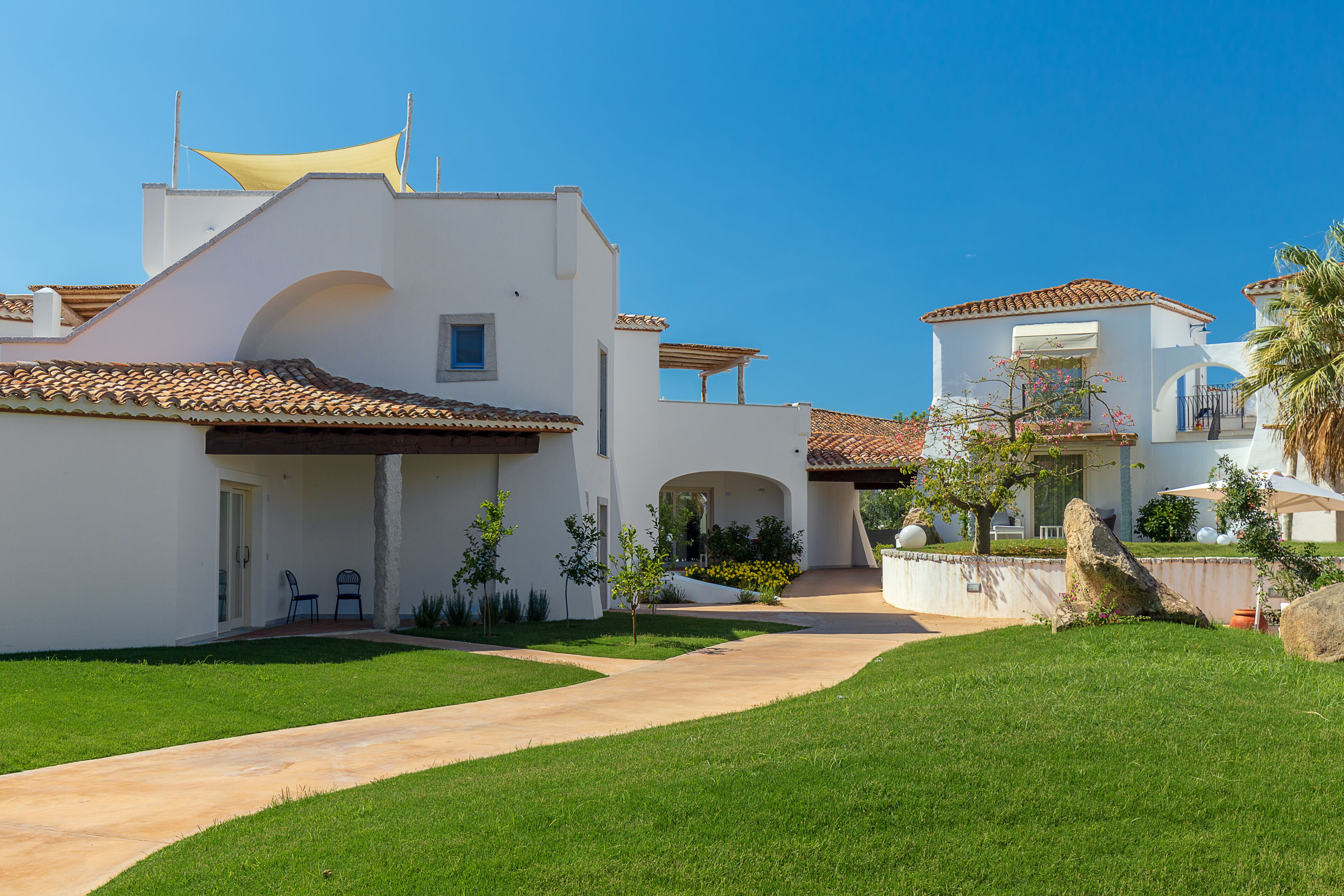 A modern house with a tiled roof, a paved driveway, and a well-maintained lawn.