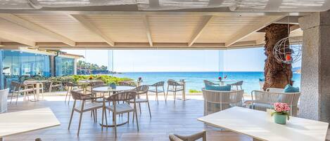 An outdoor seating area with tables and chairs, overlooking a body of water.
