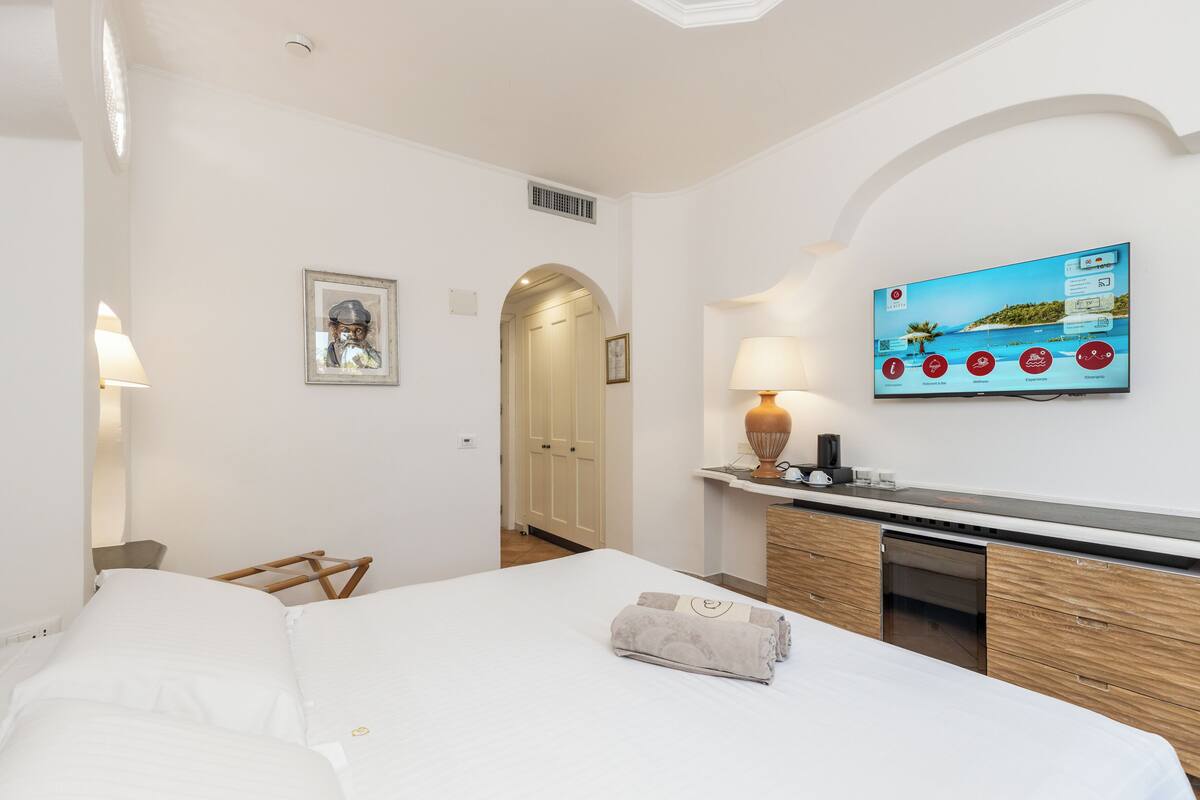 Une chambre d’hôtel comprenant un lit, un bureau, une télévision et une porte donnant sur une autre pièce.