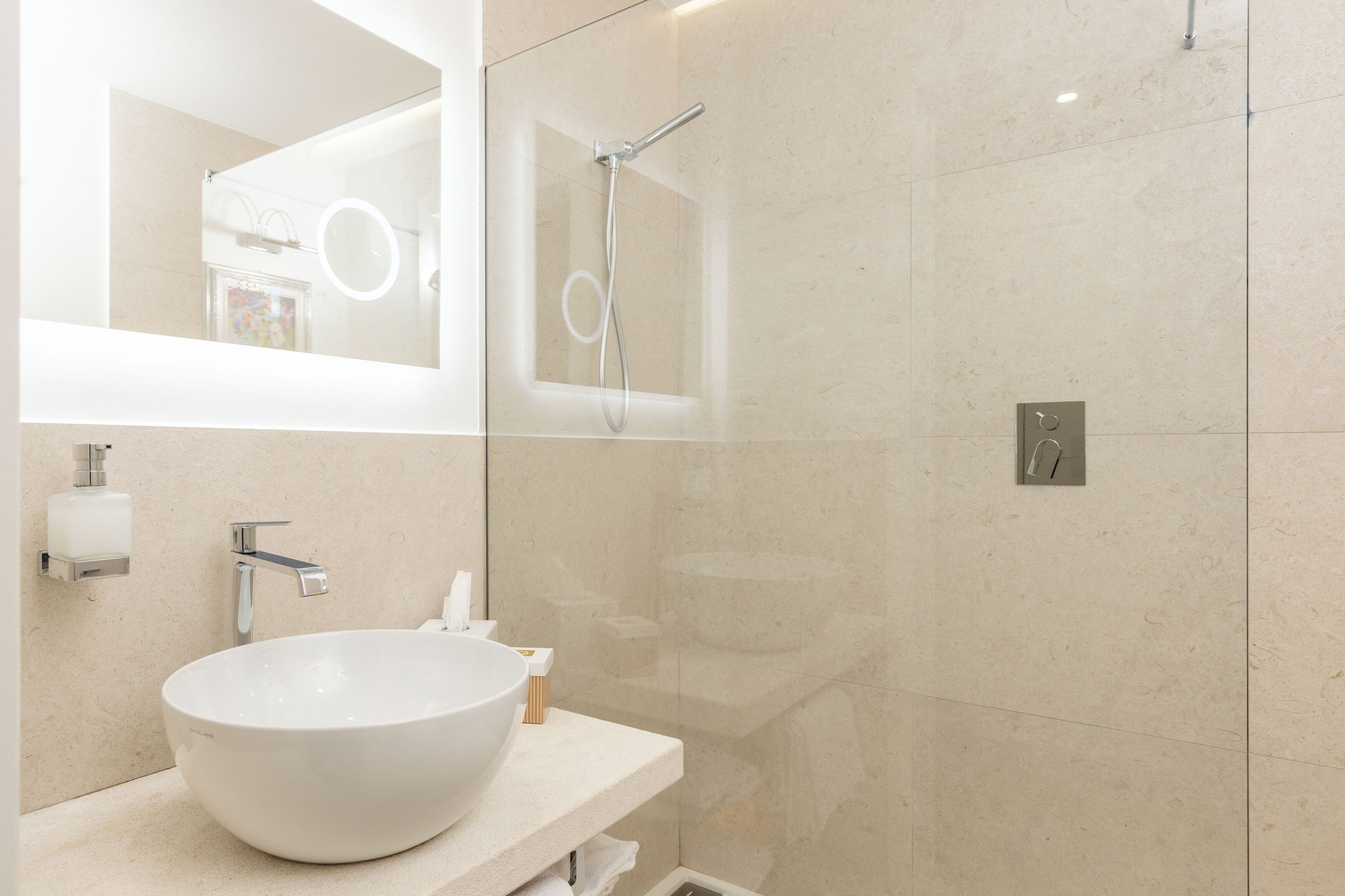 A modern bathroom with a large white sink, a mirror, and a glass-enclosed shower.