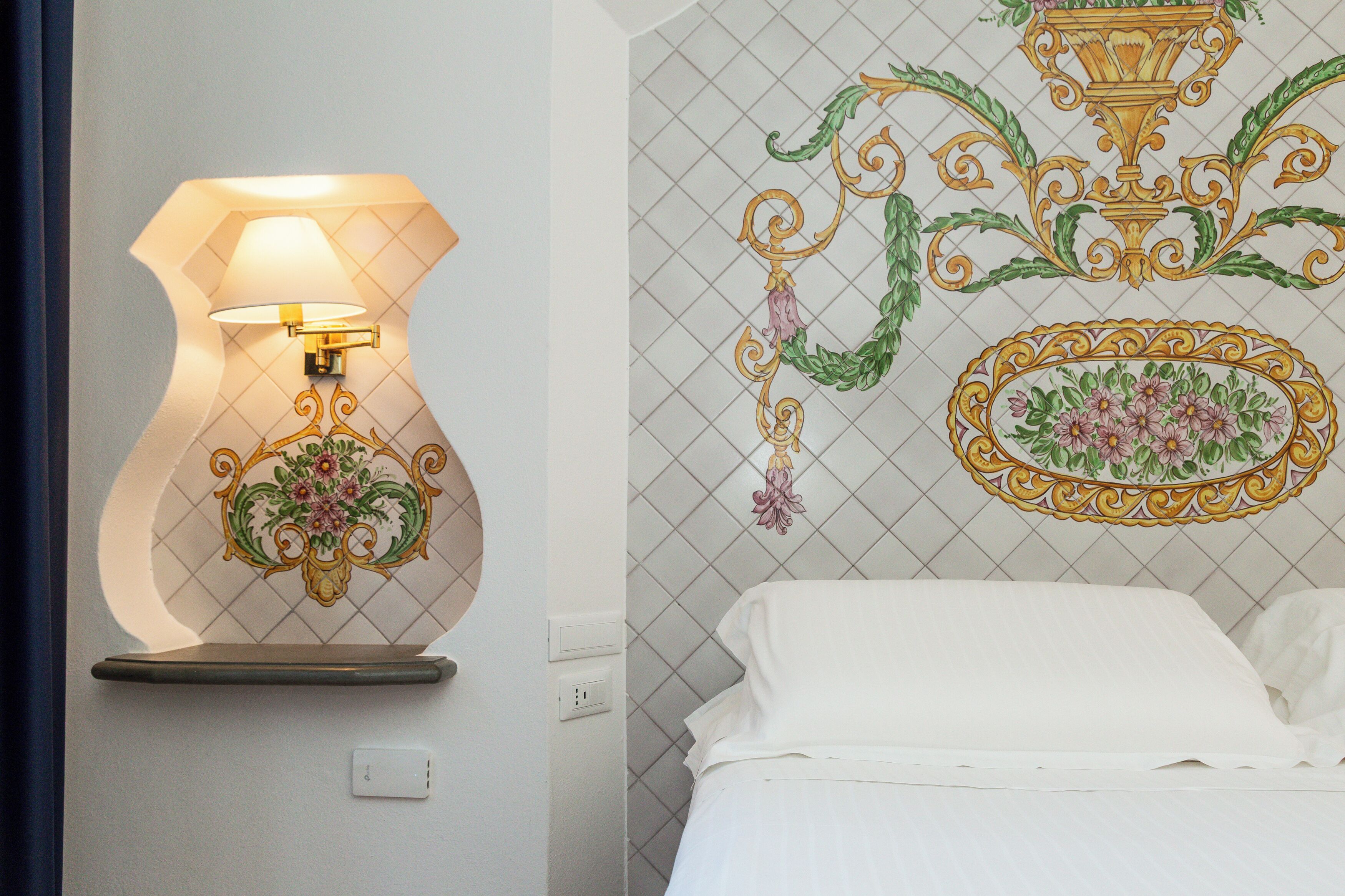 A bathroom with a wall-mounted lamp and decorative tiles.