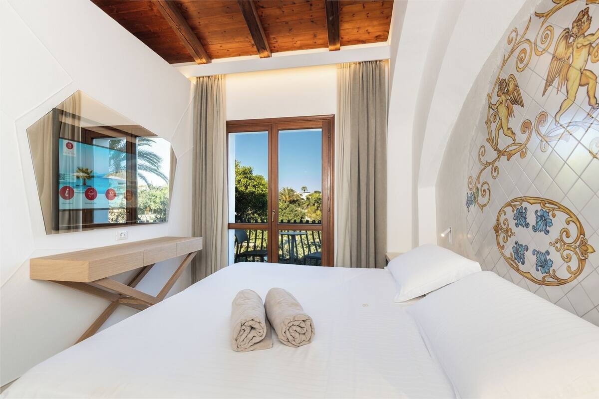 Une chambre d’hôtel avec un lit, une fenêtre avec des rideaux, un plafond en bois et un mur recouvert de carreaux avec un motif décoratif.