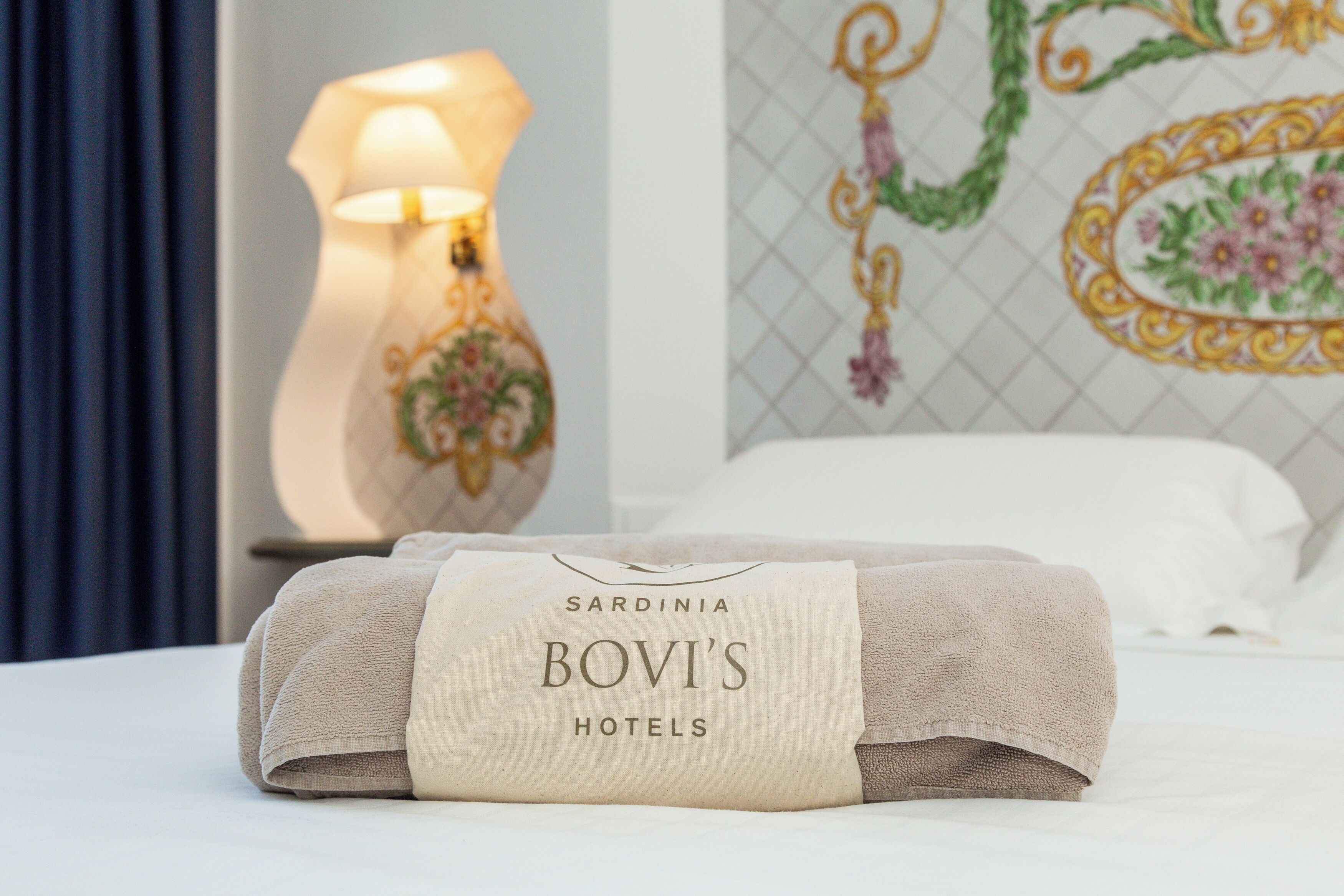 A neatly folded towel with a label reading "Sardinia Bovi's Hotels" on a bed.