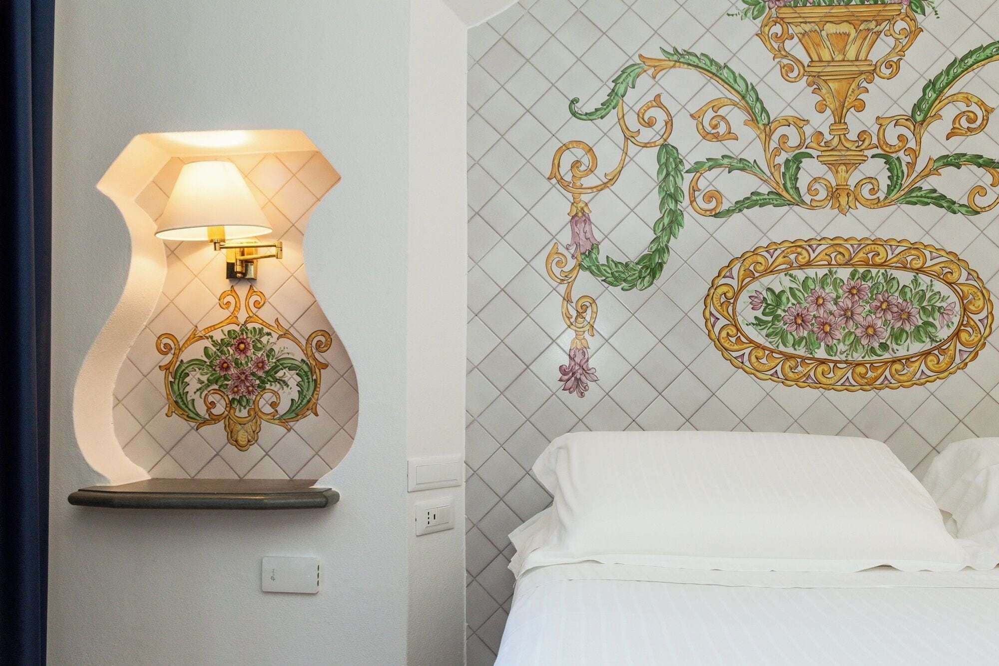 Una habitación de hotel con una lámpara de pared, un panel decorativo y una cama.