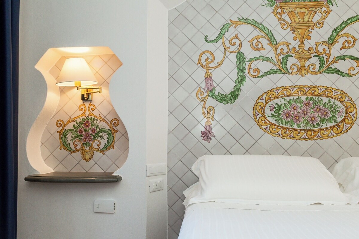 Una habitación de hotel con una lámpara de pared, un panel decorativo y una cama.