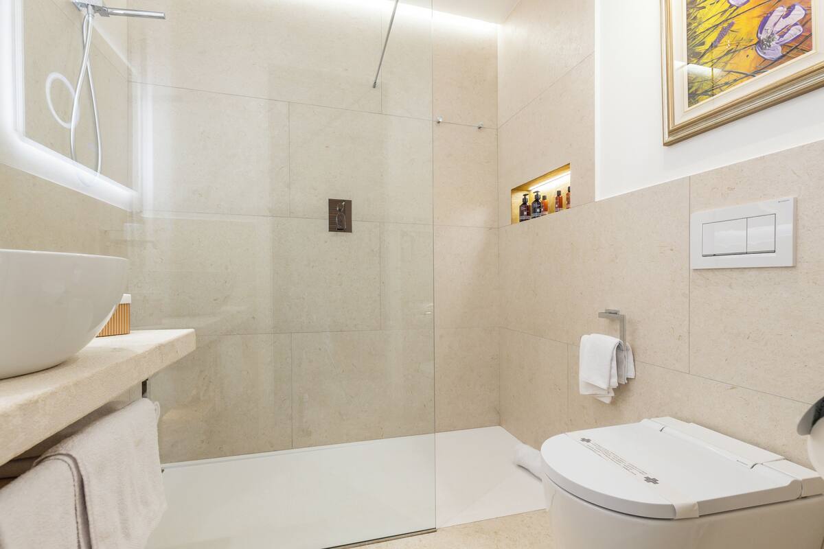 Une salle de bain moderne avec une douche à parois de verre, une baignoire blanche et un plan de toilette doté d’un lavabo et d’un porte-serviettes.