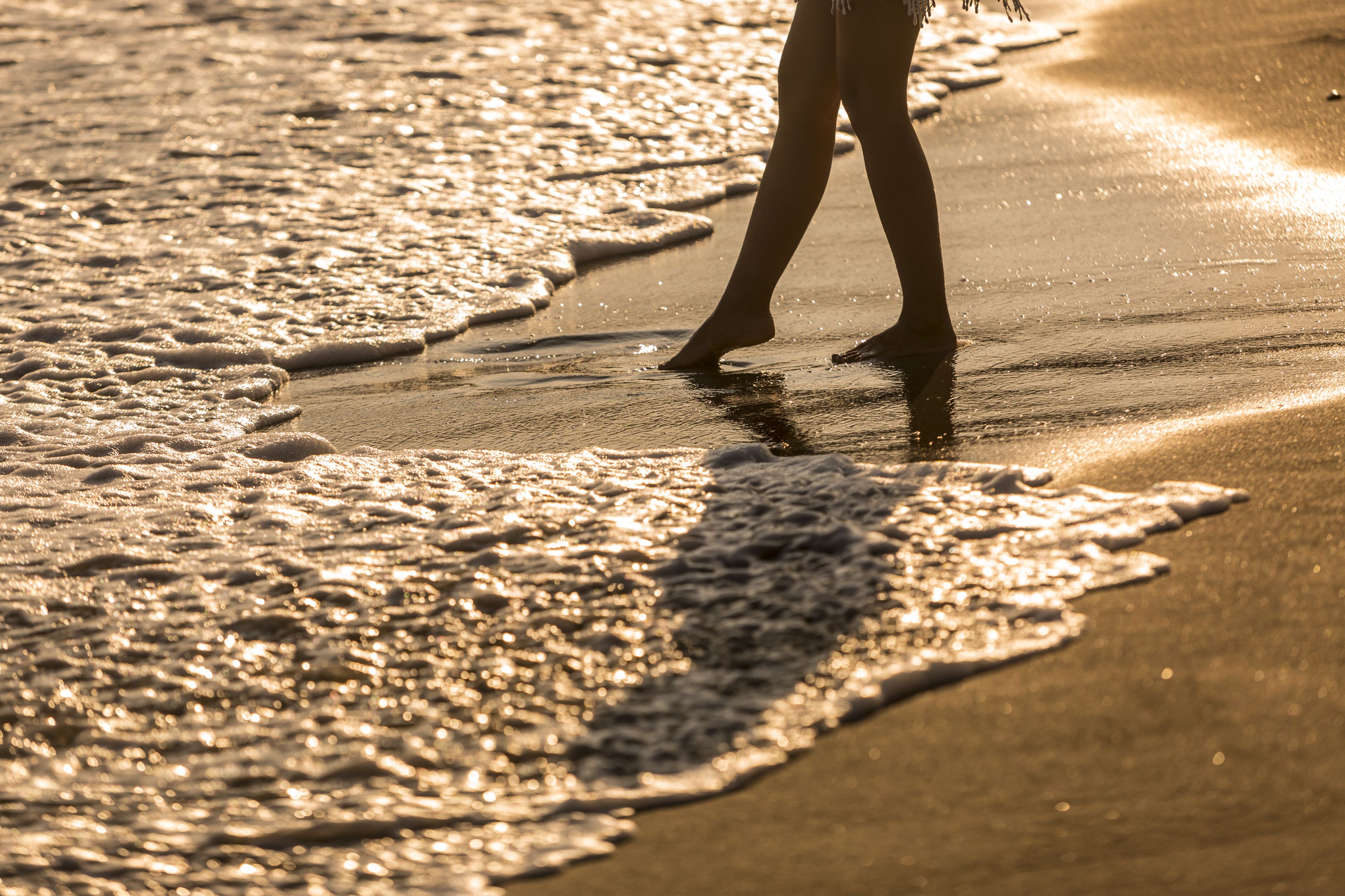 A beach scene with waves and a person standing in the water.